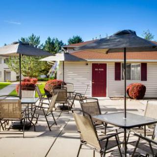 Outdoor patio area with tables, chairs, and umbrellas on a sunny day.