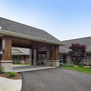 A modern building entrance with a covered driveway and landscaped surroundings.