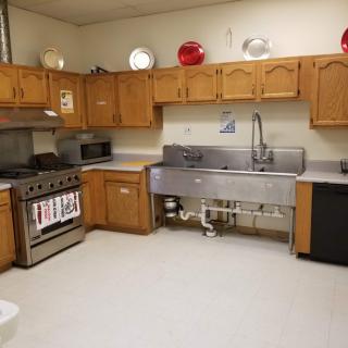 A spacious kitchen with wooden cabinets, a large sink, and various appliances.