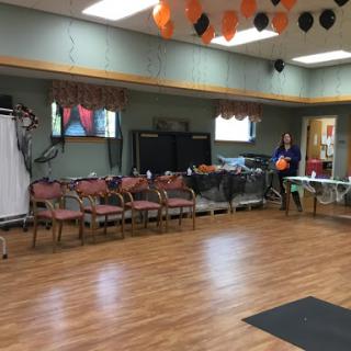 An indoor community center setup for an event, featuring chairs and tables arranged neatly with festive orange and black decorations.