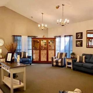 A cozy living room featuring blue sofas, decorative items, and chandeliers with ample natural light from multiple windows.