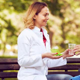 A woman in a white coat sitting on a park bench, engaging in conversation.