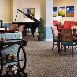 A cozy living room featuring a grand piano, seating area, and colorful artwork on the walls.
