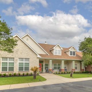 A suburban residential house with a well-maintained lawn and a cloudy sky.