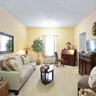 A cozy living room with a sofa, coffee table, and TV, featuring warm lighting and decorative elements.