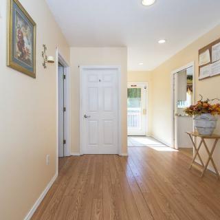 A well-lit hallway with wooden flooring and home decor.