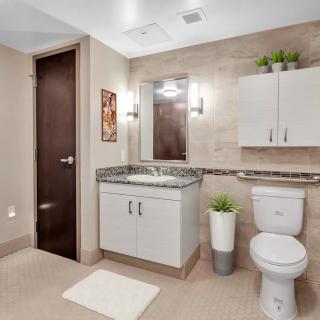 A modern and clean bathroom with a vanity, mirror, toilet, and decorative elements.