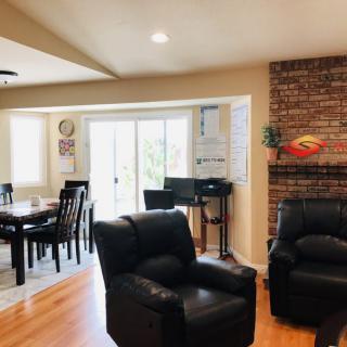 A cozy living room with leather chairs, a brick fireplace, and a view of the dining area.