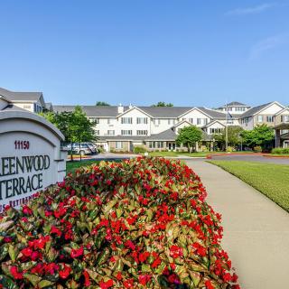 A view of a residential complex with well-maintained gardens and a welcoming entrance sign.