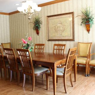 A well-decorated dining room featuring a wooden table and matching chairs, complemented by floral arrangements and wall art.
