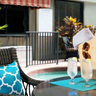 A relaxing poolside setup with iced drinks, sunglasses, and a hat on patio furniture.