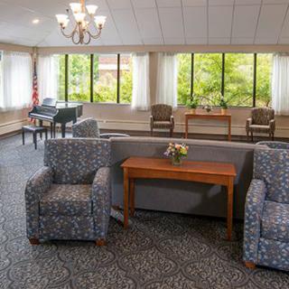 A spacious lounge area with comfortable seating, a piano, and large windows.