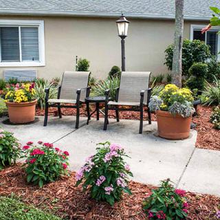A well-maintained patio with two chairs surrounded by potted plants and colorful flowers.