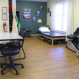 A physical therapy clinic room equipped with treatment table and exercise equipment.