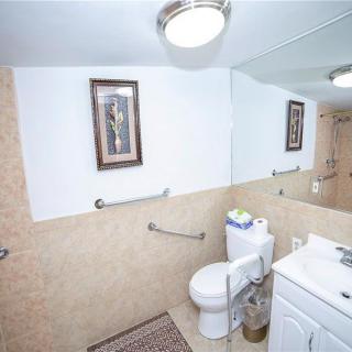 A clean bathroom featuring a toilet, sink, and large mirror with a decorative framed picture on the wall.