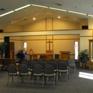 A view of a church interior with rows of chairs facing an altar.