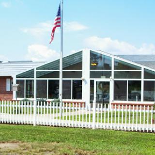 A modern building with a glass front and an American flag flying in the foreground.