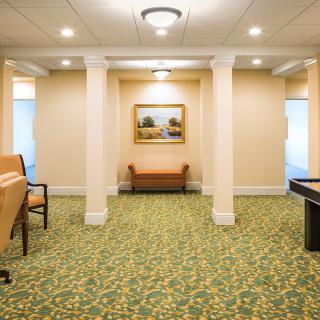 A well-lit hallway featuring seating and artwork with a carpeted floor.