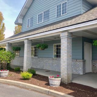 A blue house with a large porch, columns, and well-maintained landscaping.