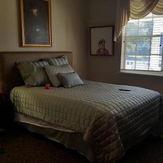 A cozy bedroom with a neatly made bed, adorned with pillows, and sunlight filtering through the window.
