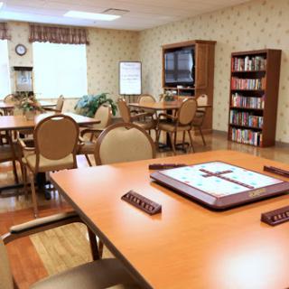 A well-furnished community room with tables and bookshelves, designed for group activities and reading.