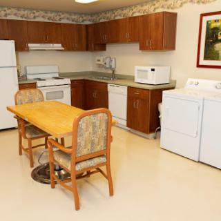 A spacious kitchen featuring modern appliances, a wooden dining table, and laundry facilities.