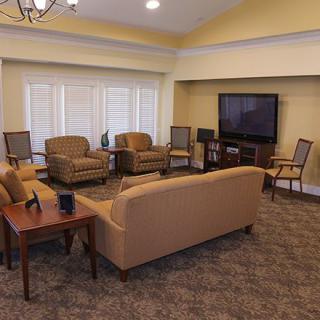 A cozy living room with a sofa, multiple chairs, a television, and a coffee table arranged on a carpeted floor.