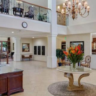 Elegant lobby with a grand chandelier and floral centerpiece on a round table.