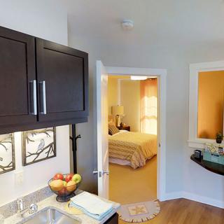 Modern kitchen area with a glimpse into a cozy bedroom.