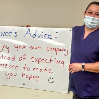 A nurse holding a sign with advice on enjoying your own company.