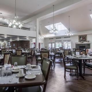 Spacious dining area with neatly arranged tables and elegant chandeliers.