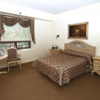 A well-furnished hotel bedroom with a double bed, side tables, and a window with drapes.