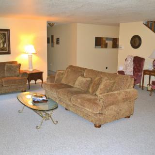 A cozy living room with a sofa, armchair, coffee table, and lamp.