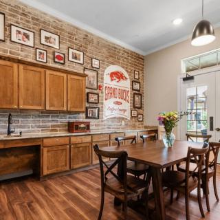 A cozy kitchen and dining area featuring wooden cabinets, a brick wall adorned with pictures, and a hardwood floor.