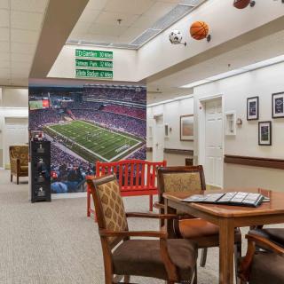 A sports-themed lounge area featuring a large football stadium mural, seating arrangements, and decorative elements on the walls and ceiling.