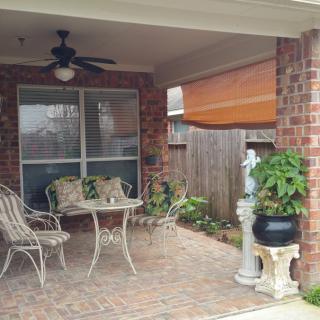 A cozy patio area featuring a table and chairs, surrounded by plants and brick walls.