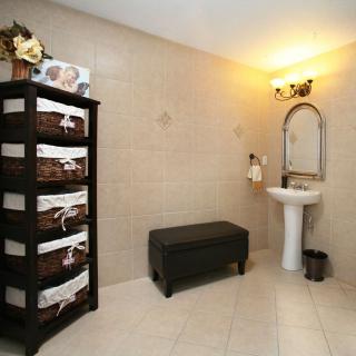A neatly organized bathroom featuring a pedestal sink, storage baskets on shelves, and a small bench.