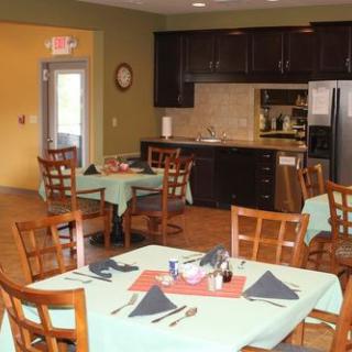 A cozy dining area with neatly set tables and chairs, adjacent to a kitchen.