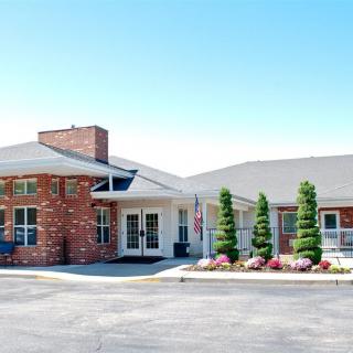 A single-story brick building with a landscaped entrance and driveway under a clear blue sky.