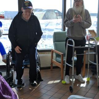 Two seniors engaged in a rehabilitation activity in a communal area.