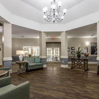 A spacious lobby with elegant decor, featuring a chandelier and comfortable seating.