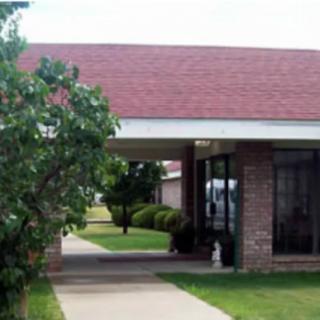 A small building entrance with a pathway and surrounding greenery.