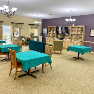 A spacious dining area with tables and chairs, well-lit by chandeliers.