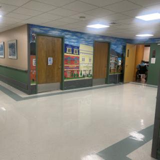 A well-lit hallway featuring doors and colorful murals on the walls.