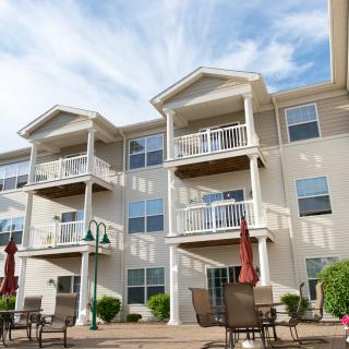 A modern apartment building with balconies and a well-furnished patio area.