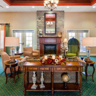 An elegantly decorated living room featuring a fireplace, armchairs, and a chandelier.