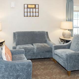 A cozy living room setup featuring a blue sofa and armchairs, complemented by decorative lamps.