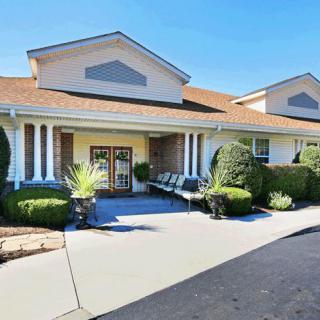 A well-maintained building entrance with columns and landscaped surroundings.