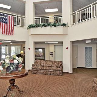 A spacious lobby with a couch, flowers on a center table, and an American flag on display.