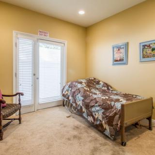 A cozy bedroom with a single bed, decorated with paintings and bathed in warm lighting.